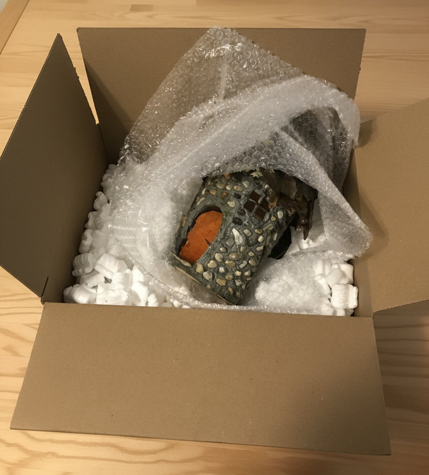 Cardboard box with bubble wrap and a wrapped object on a table.